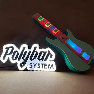 May include: A light-up guitar-shaped game controller with a green body and a red and blue neck. The controller has illuminated buttons. A white and black "Polybar SYSTEM" sign is also in the image.
