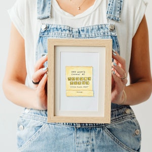 K&ouml;nnte beinhalten: Eine gerahmte Illustration eines gelben Schilds mit dem Text "SEE WHAT'S COOKIN' AT WAFFLE HOUSE GOOD FOOD FAST" in schwarzer Handschrift.