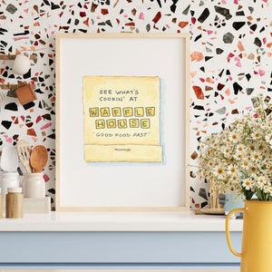 K&ouml;nnte beinhalten: Eine Aquarellillustration eines gelben Streichholzschachtels mit dem Text "See what's cookin' at Waffle House - Good Food Fast" darauf.