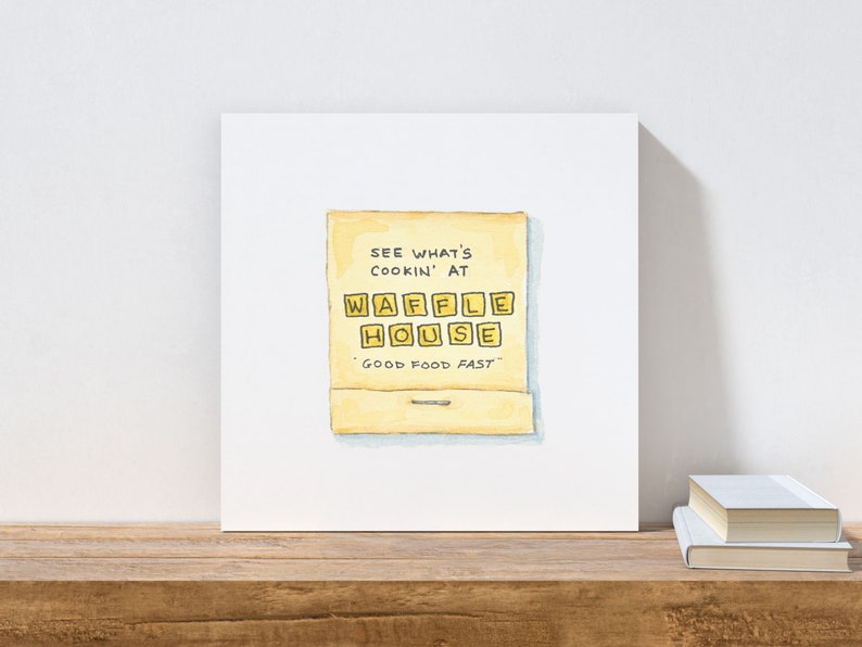 K&ouml;nnte beinhalten: Eine Aquarellillustration eines Streichholzschachtels mit dem Text "See what's cookin' at Waffle House - Good food fast" auf gelbem Hintergrund.