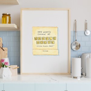 K&ouml;nnte beinhalten: Ein gerahmter Druck einer Aquarellillustration einer gelben Streichholzschachtel mit dem Text "See what's cookin' at Waffle House" und "Good food fast" darauf.