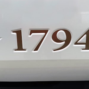 May include: A white surface with a brown star and the number 1794.