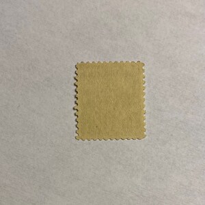 Puede incluir: Un sello postal marr&oacute;n con borde festoneado.