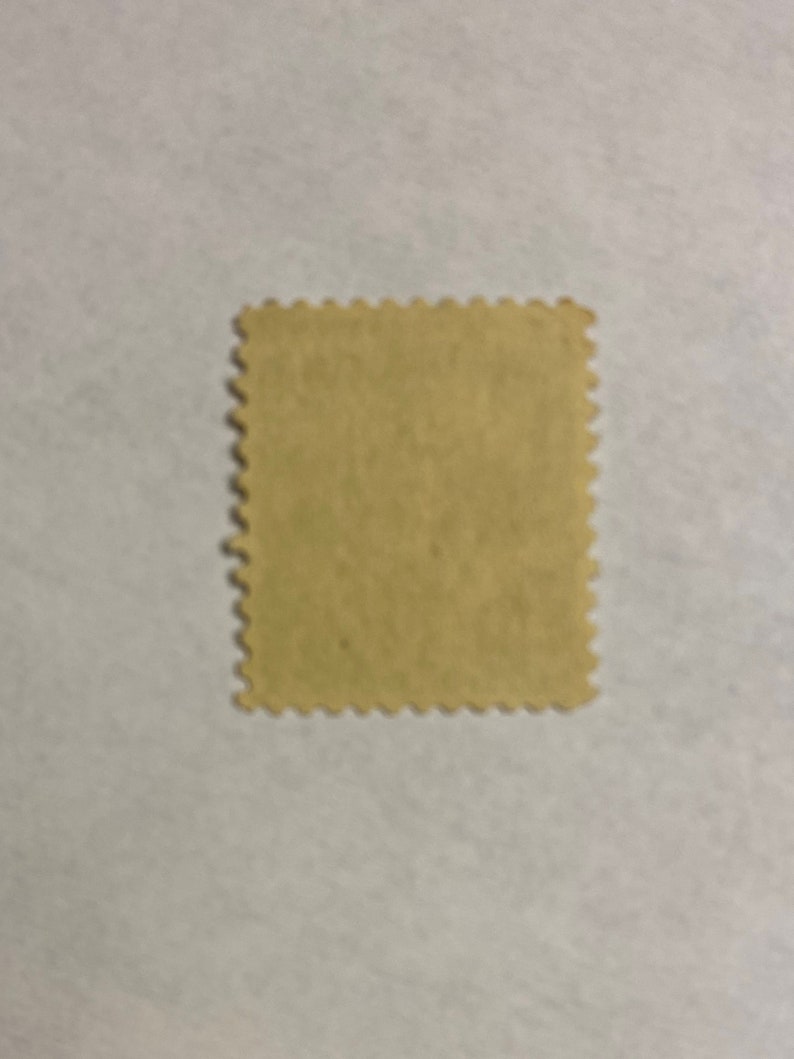 Puede incluir: Un sello postal de color beige con un borde festoneado.