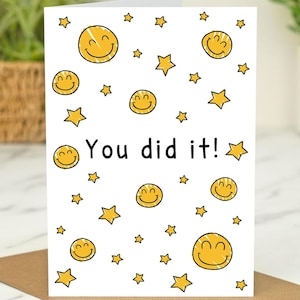 Könnte beinhalten: Eine weiße Karte mit einem gelben Smiley-Muster und dem Text "You did it!" in Schwarz. Die Karte ist mit gelben Sternen verziert.
