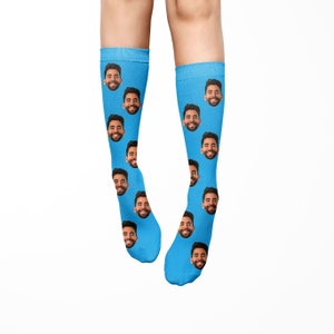 K&ouml;nnte beinhalten: Ein Paar blaue Socken mit einem sich wiederholenden Muster eines M&auml;nnergesichts.