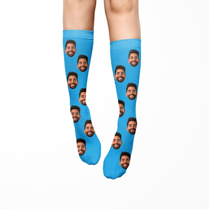 K&ouml;nnte beinhalten: Ein Paar blaue Socken mit einem sich wiederholenden Muster eines M&auml;nnergesichts.