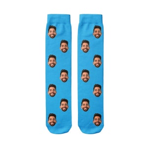 K&ouml;nnte beinhalten: Ein Paar blaue Socken mit einem sich wiederholenden Muster eines M&auml;nnergesichts.