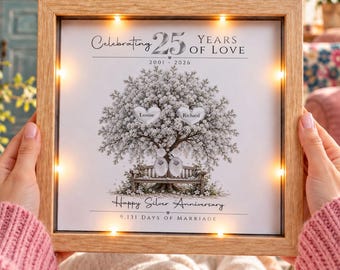 May include: A square wooden shadow box frame with integrated LED lights surrounding a central print. The artwork features a tree with two heart-shaped leaves labeled Louise and Richard, text reading Celebrating 25 Years of Love, 2001-2024, Happy Silver Anniversary, and 9,131 Days of Marriage.