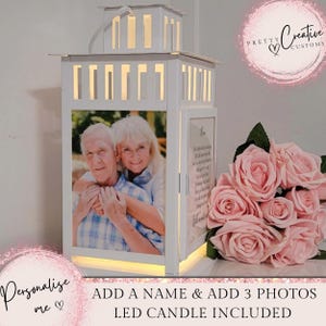 Puede incluir: Linterna de madera blanca con una foto de una pareja mayor en su interior. La linterna tiene una vela LED incorporada y espacio para tres fotos. El texto "ADD A NAME & ADD 3 PHOTOS LED CANDLE INCLUDED" está en la parte inferior de la imagen.