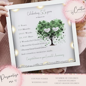 May include: A white framed print with a green tree and hearts. The text reads "Celebrating 55 years 20th March 1969", "55 Years", "660 Months", "2860 Weeks", "20,089 Days", "2 Wonderful Children", "4 Beautiful Grandchildren", "3 Precious Great Grandchildren", "And countless memories made. Congratulations on your Emerald Anniversary". The names "John" and "Grace" are written on the hearts.