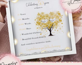 May include: A white frame with a gold and white heart tree design. The text reads "Celebrating 50 years 20th March 1974", "John", "Grace", "50 Years", "600 Months", "2,600 Weeks", "18,262 Days", "1 Wonderful Children", "7 Beautiful Grandchildren", "And countless memories made. Congratulations on your Golden Anniversary".