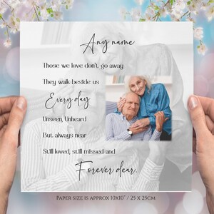 May include: A black and white photograph of an older couple embracing. The photo is on a white background with black text overlay that reads "Those we love don't go away. They walk beside us Every day. Unseen, Unheard. But always near. Still loved, still missed and Forever dear." The text also includes the words "Any name" at the top and "PAPER SIZE IS APPROX 10x10" / 25 x 25CM" at the bottom.