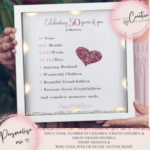 May include: A white frame with a glittery pink heart and a personalized message celebrating 50 years of someone's life. The message includes the number of years, months, weeks, and days, as well as the number of family members. The text reads "Celebrating 50 years of you 20th March 1974 50 Years 600 Months 2,600 Weeks 18,262 Days 1 Amazing Husband 3 Wonderful Children 8 Beautiful Grandchildren 5 Precious Great Grandchildren And countless memories made. Happy 65th birthday xxx".