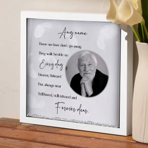 May include: White framed memorial box with a black and white photo of a man and a poem that reads "Those we love don't go away, They walk beside us Every day, Unseen, Unheard, But always near, Still loved, still missed and Forever dear."