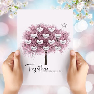 Op de afbeelding: Een roze en witte kersenboom met harten aan de takken. Elk hart heeft een naam erop geschreven. De tekst onderaan de afbeelding luidt "Samen is onze favoriete plek om te zijn."