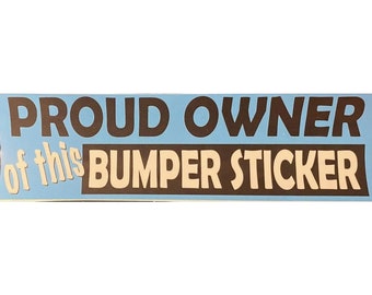 May include: A blue and white bumper sticker that reads "Proud Owner of this Bumper Sticker".