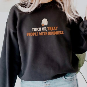 May include: Black sweatshirt with a white ghost holding a pumpkin and the text "Trick or Treat People with Kindness".