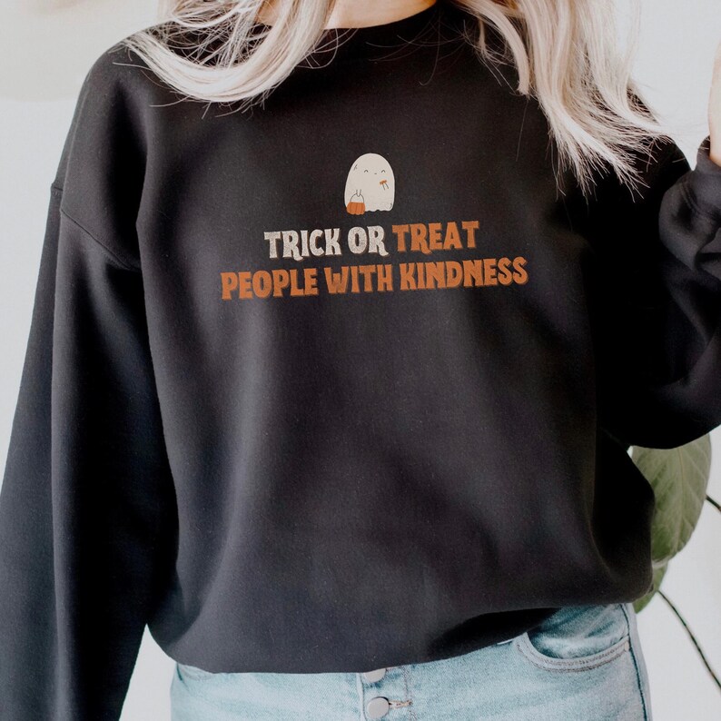 May include: Black sweatshirt with a white ghost holding a pumpkin and the text "Trick or Treat People with Kindness".
