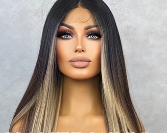 May include: A long, layered wig with dark brown and blonde highlights. The wig is styled with long, straight strands and features the text "HAUTE WIGS" across the top. The wig is displayed on a mannequin head.