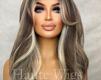 May include: Long, wavy, light brown wig with blonde highlights. The wig is styled with a side part and has a natural, flowing look.