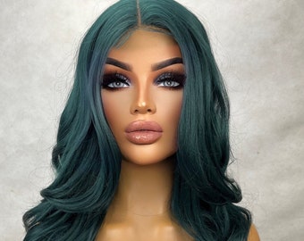 May include: A long, dark green wig with loose waves. The wig is styled with a centre parting and has a natural-looking hairline.