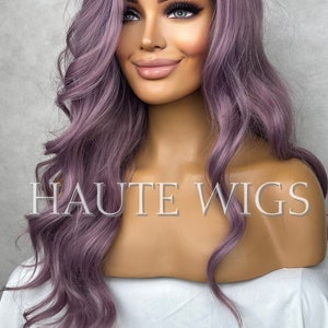 Puede incluir: Una peluca larga y ondulada de color morado con un frente de encaje. La peluca está peinada en ondas sueltas y cae hasta los hombros. La peluca está en una cabeza de maniquí. El texto "HAUTE WIGS" es visible en el pecho del maniquí.