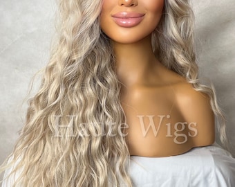 May include: A long, wavy, platinum blonde wig with a side part. The wig is styled in loose waves and falls to the shoulders. The wig is on a mannequin head.