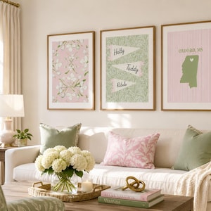 May include: A set of three framed wall art prints. The left print features a pink floral pattern. The center print displays three pennants with the text Hotty, Toddy, and Rebels. The right print shows a green map of Mississippi with the text Oxford, MS.