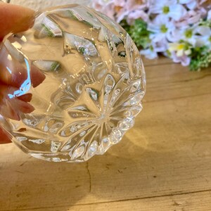 May include: A clear glass bowl with a diamond pattern on the bottom. The bowl is empty and has a slight curve to the bottom.