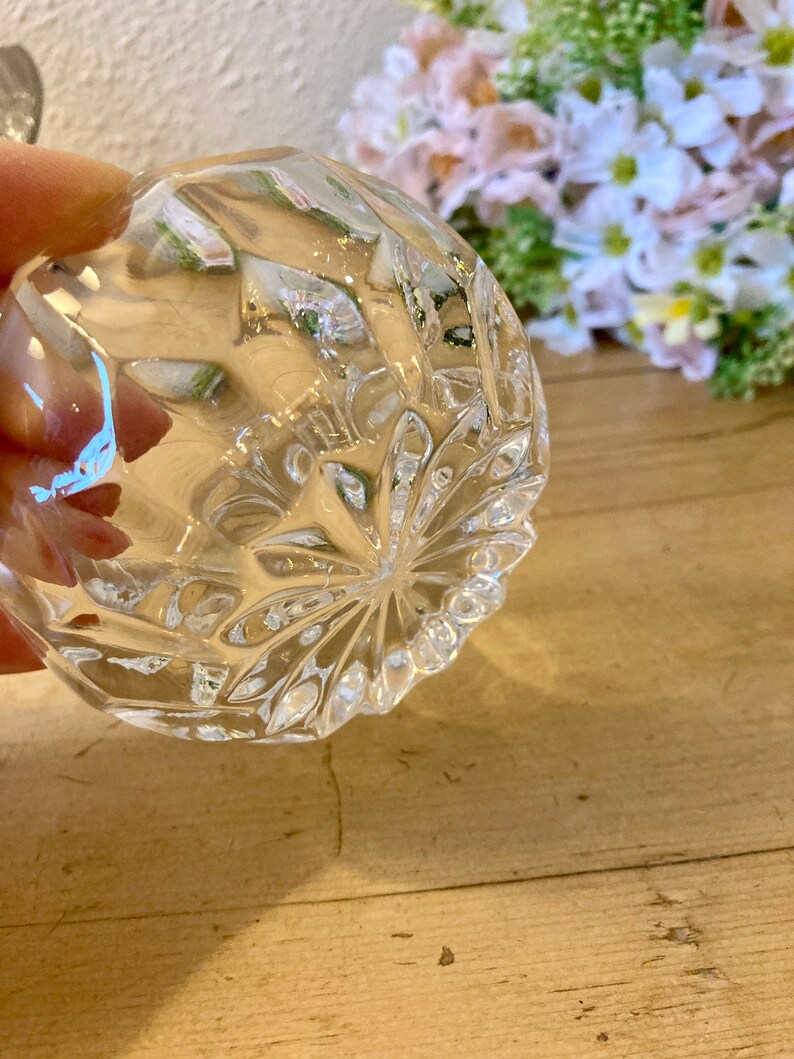 May include: A clear glass bowl with a diamond pattern on the bottom. The bowl is empty and has a slight curve to the bottom.