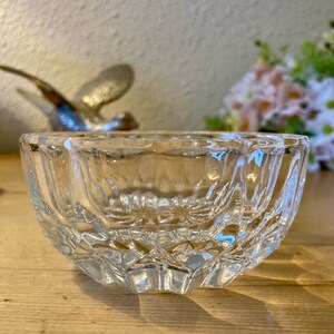 May include: A clear glass bowl with a cut-glass design. The bowl is sitting on a wooden surface.