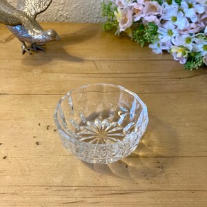 May include: A clear glass bowl with a cut crystal design. The bowl is round and has a wide rim.