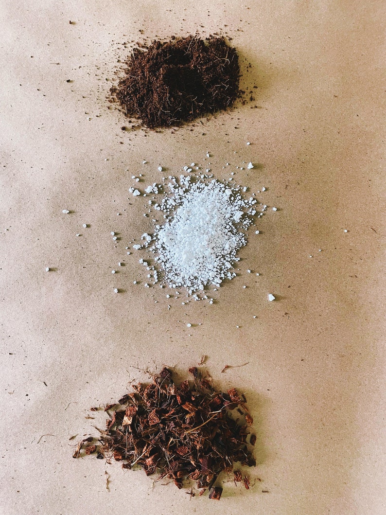 May include: An overhead shot displays three distinct piles of gardening materials. At the top is a dark brown, fibrous substance, followed by a pile of white, granular material, and at the bottom, a pile of brown, shredded pieces.