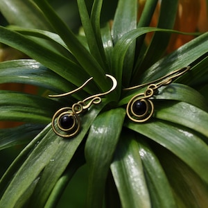 May include: A pair of gold earrings with black beads hanging from a spiral design.