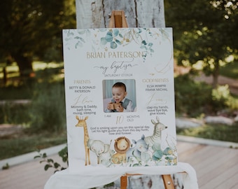 May include: A white sign with a green and gold floral design announcing a baby's baptism. The sign includes the baby's name, Brian Paterson, the date of the baptism, and a photo of the baby. The sign also includes the names of the baby's parents and godparents. The sign is decorated with a variety of animals, including a giraffe, a lion, a zebra, and a rhino.