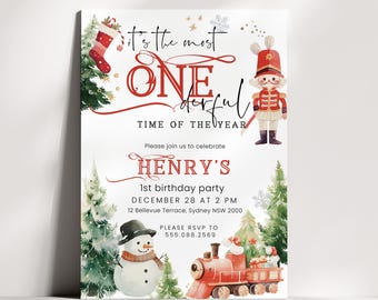 May include: A white birthday invitation card featuring watercolor illustrations of a nutcracker, a snowman, a red train, and a Christmas stocking. The text reads: It's the most ONE-derful TIME OF THE YEAR, HENRY'S 1st birthday party, DECEMBER 28 AT 2 PM.