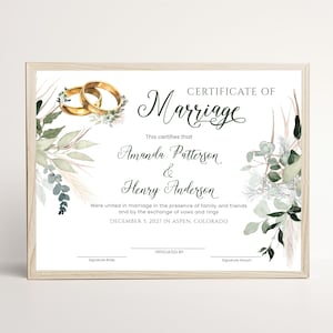Puede incluir: Un certificado de matrimonio rectangular en un marco de madera clara. El documento presenta el texto Certificate of Marriage, Amanda Patterson and Henry Anderson, y December 5, 2027 in Aspen, Colorado, decorado con anillos dorados y follaje en acuarela.