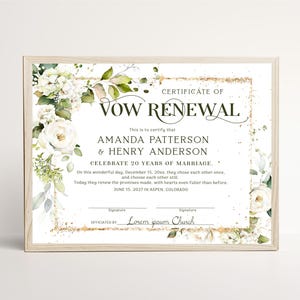 May include: A vow renewal certificate in a light wood frame featuring white floral arrangements on the left and right sides. The text reads CERTIFICATE OF VOW RENEWAL, AMANDA PATTERSON & HENRY ANDERSON, CELEBRATE 20 YEARS OF MARRIAGE, and Lorem ipsum Church.