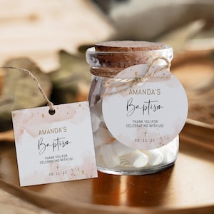 Könnte beinhalten: Ein Glas mit Korkdeckel und einem Etikett mit der Aufschrift "Amandas Taufe". Das Etikett hat ein Aquarelldesign mit goldenen Akzenten. Das Glas ist mit weißen Süßigkeiten gefüllt und mit Bindfaden gebunden.
