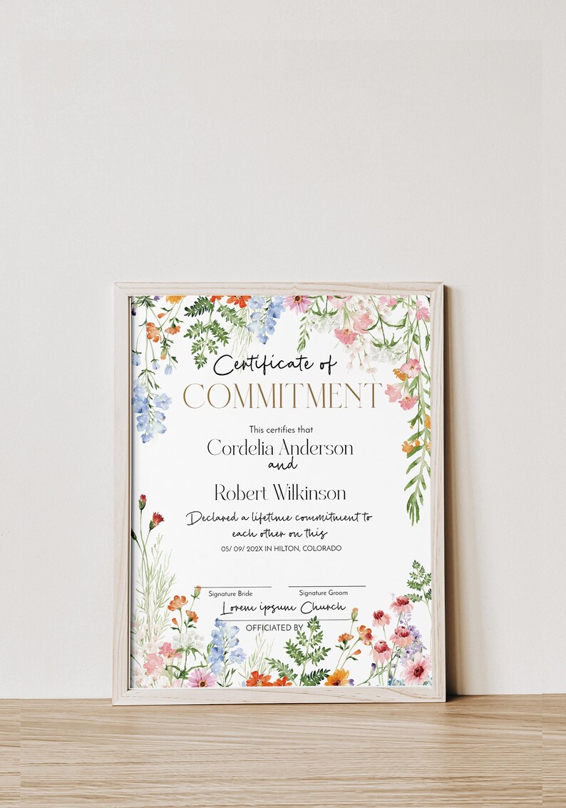 May include: A framed certificate with floral decorations. The text reads "Certificate of Commitment" and lists names and a commitment date. The certificate is in a light wood frame.