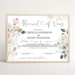 Op de afbeelding: Een certificaat voor de vernieuwing van huwelijksgeloften in een lichthouten lijst, met aquarel roze rozen en groen blad. De tekst bevat de namen Cordelia Anderson en Henry Wilkinson, 20 jaar getrouwd, datum 15 september 20XX en Hilton, Colorado.