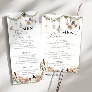 Könnte beinhalten: Zwei weiße Menükarten mit einer Aquarellillustration von hängenden Weihnachtsschmuck und Tannengrün oben und unten. Der Text lautet Dinner Menu mit Abschnitten für Appetizer, Entree und Dessert und listet verschiedene Speisen auf.