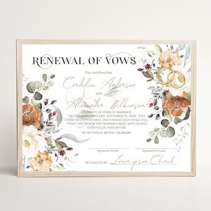 May include: A framed Renewal of Vows certificate featuring floral illustrations in shades of rust, cream, and sage green. The text includes the names Cordelia Anderson and Alexander Wilkinson, with two gold rings depicted on the right side of the document.