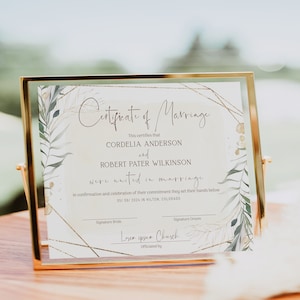 May include: A framed certificate of marriage with gold trim. The certificate features the names Cordelia Anderson and Robert Pater Wilkinson, with the date 05/09/2024. The design includes botanical illustrations and geometric gold accents.
