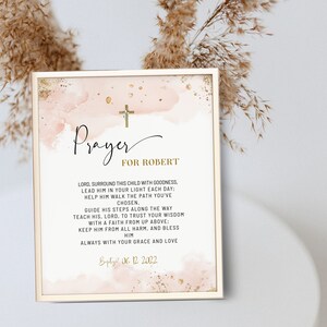 Könnte beinhalten: Gerahmter Druck mit einem goldenen Kreuz und dem Wort "Prayer" in eleganter Schrift. Der Text "FOR ROBERT" steht unter dem Wort "Prayer". Der Druck hat einen Aquarellhintergrund in Rosa- und Goldtönen. Der untere Teil des Drucks lautet "Baptized 06.12.2022".