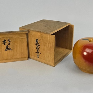 May include: A wooden apple-shaped container with a glossy red and yellow finish, next to two wooden boxes with Japanese characters. The boxes are open, revealing their interior.