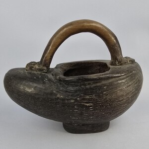 May include: A dark brown wooden bowl with a carved handle. The bowl is shaped like a gourd and has a smooth, polished finish.