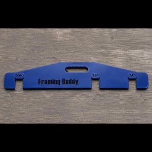 May include: A blue plastic framing tool labeled Framing Buddy with a central handle cutout. The tool features three distinct slots along the bottom edge, clearly marked with the text ZERO, 16", and 24" to indicate specific spacing measurements.