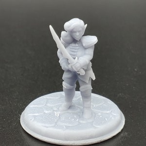 May include: A gray 3D printed miniature of an elf warrior holding a sword. The miniature is standing on a round base with a textured surface.